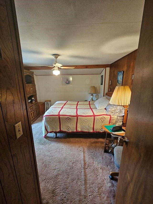 carpeted bedroom with ceiling fan and wooden walls