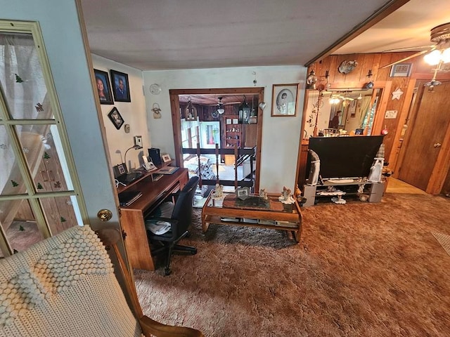 interior space featuring carpet, wooden walls, and ceiling fan