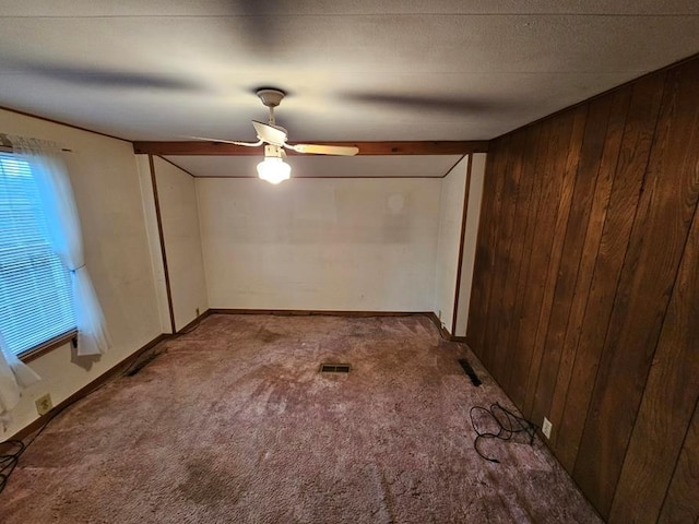 unfurnished room featuring carpet, ceiling fan, and wood walls