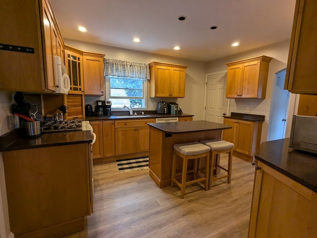 kitchen featuring a center island, a kitchen bar, light hardwood / wood-style floors, and sink