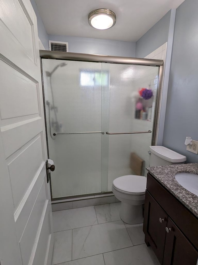 bathroom with vanity, toilet, and a shower with door