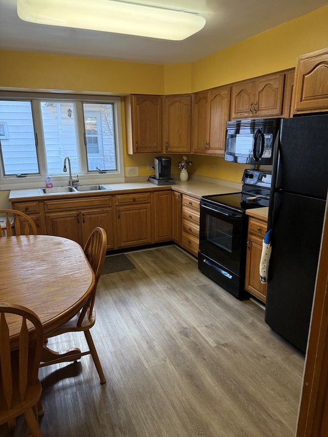 kitchen with sink, light hardwood / wood-style floors, and black appliances