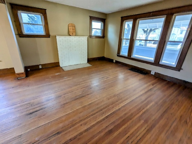 empty room with hardwood / wood-style floors and a healthy amount of sunlight