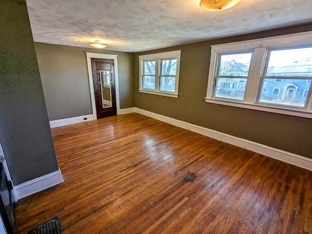 empty room with a textured ceiling and dark hardwood / wood-style flooring