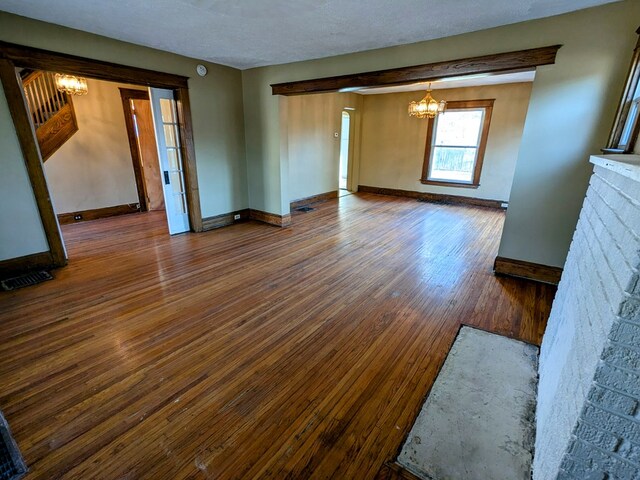 unfurnished living room featuring a fireplace, hardwood / wood-style floors, a textured ceiling, and a notable chandelier