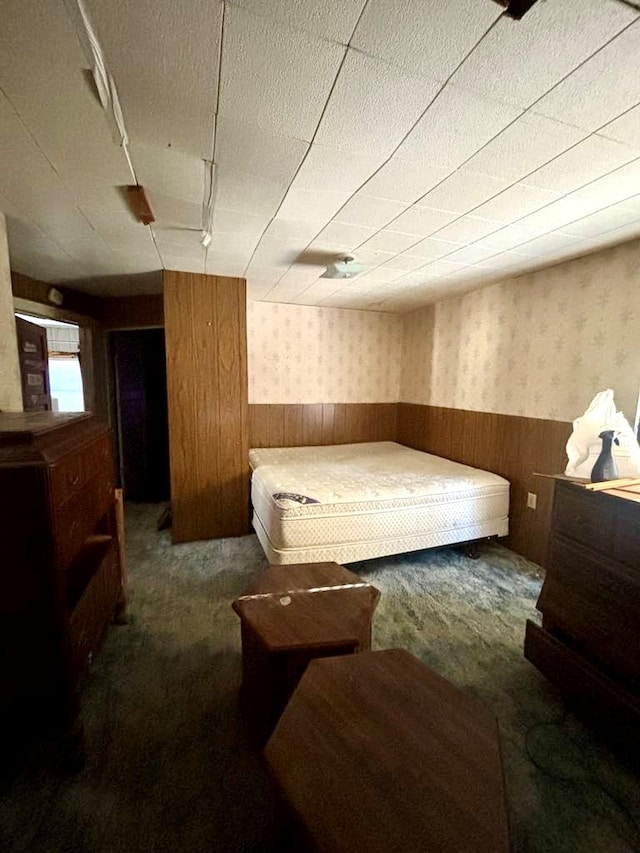 bedroom with dark colored carpet and wooden walls