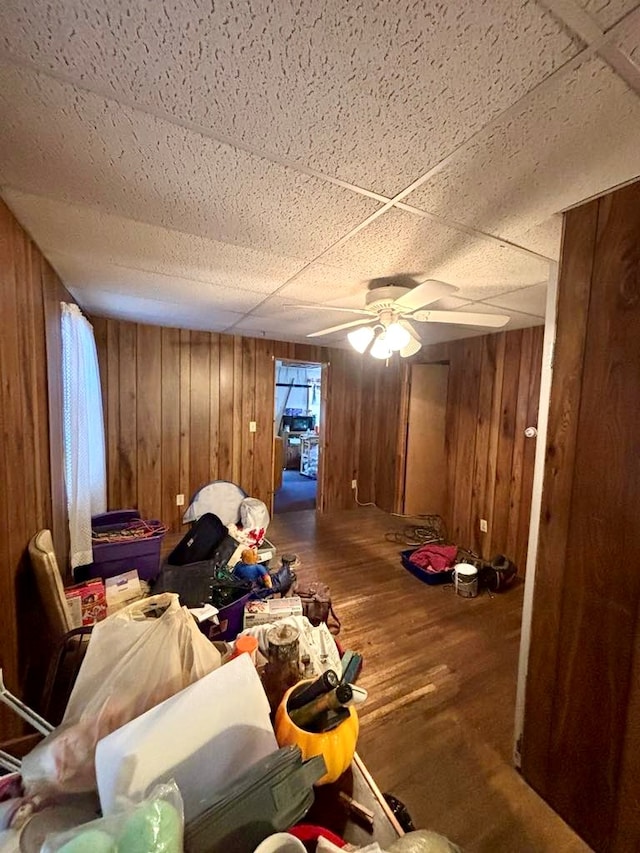 interior space featuring ceiling fan, wood-type flooring, and wooden walls