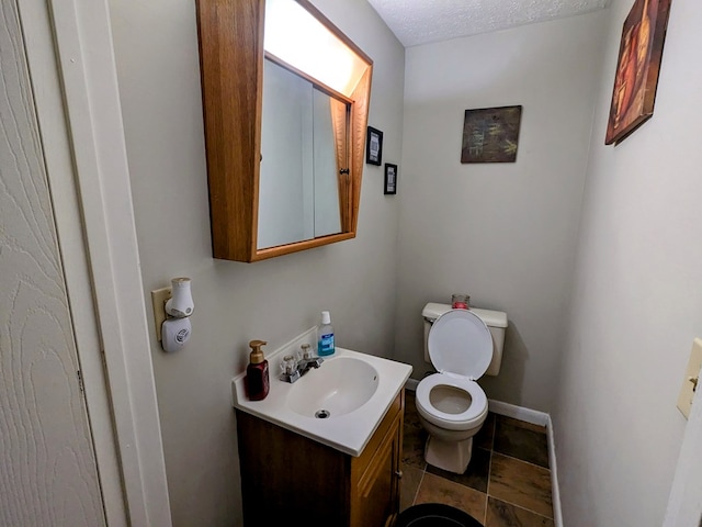 bathroom with a textured ceiling, toilet, and vanity