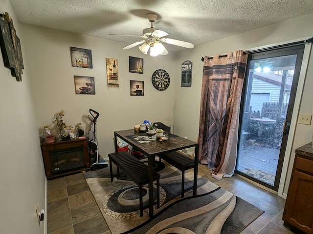 dining area featuring ceiling fan and a textured ceiling