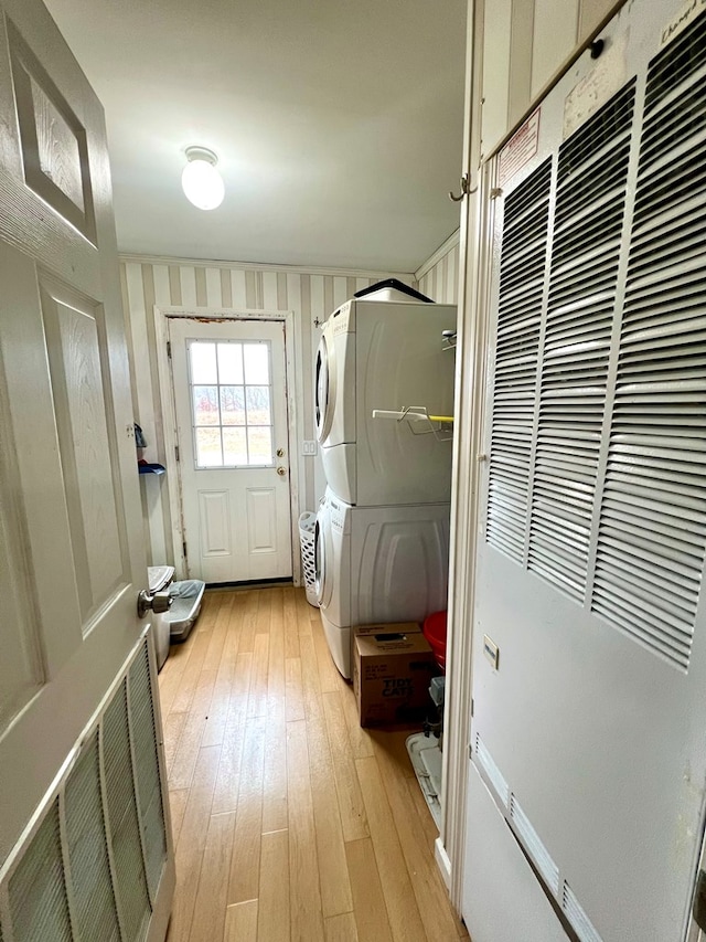 washroom with stacked washing maching and dryer and light hardwood / wood-style floors