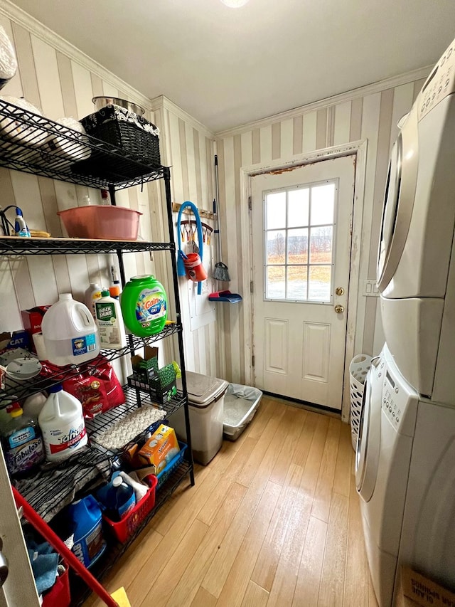 mudroom featuring stacked washer / drying machine, ornamental molding, and light hardwood / wood-style flooring