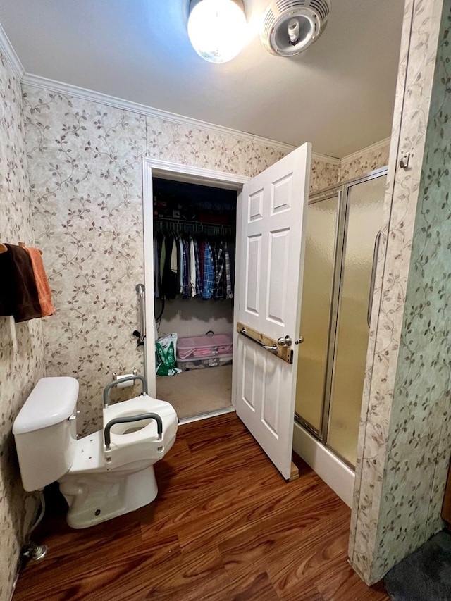 bathroom featuring crown molding, hardwood / wood-style floors, an enclosed shower, and toilet