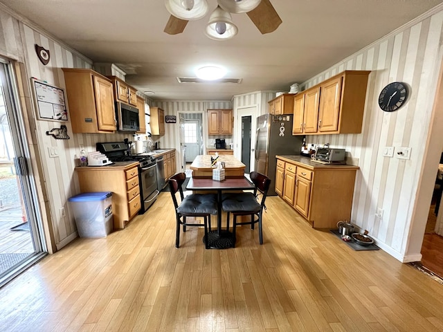 kitchen with ceiling fan, ornamental molding, appliances with stainless steel finishes, and light hardwood / wood-style flooring