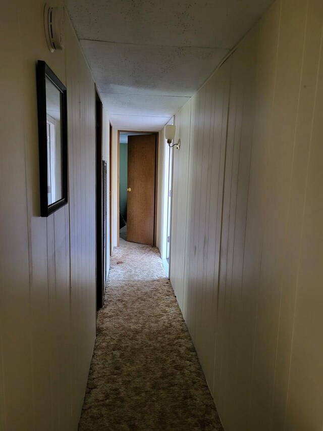 corridor with light carpet and wood walls