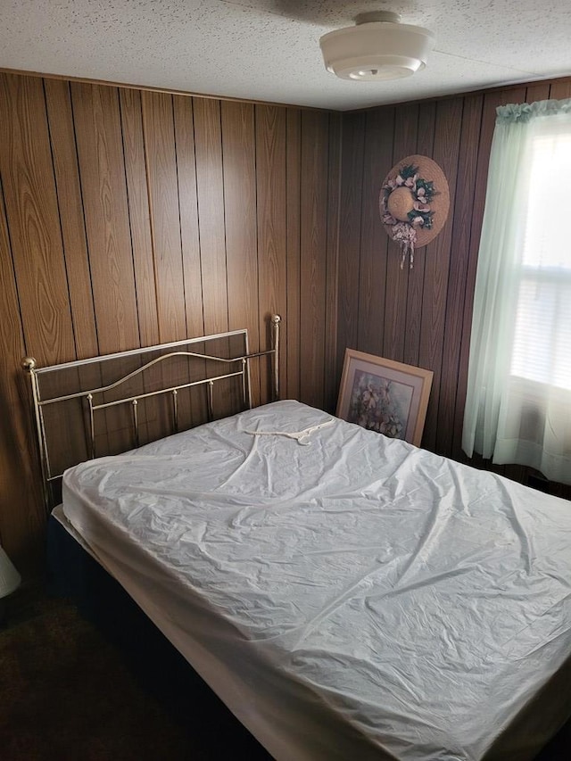 bedroom featuring wooden walls and a textured ceiling