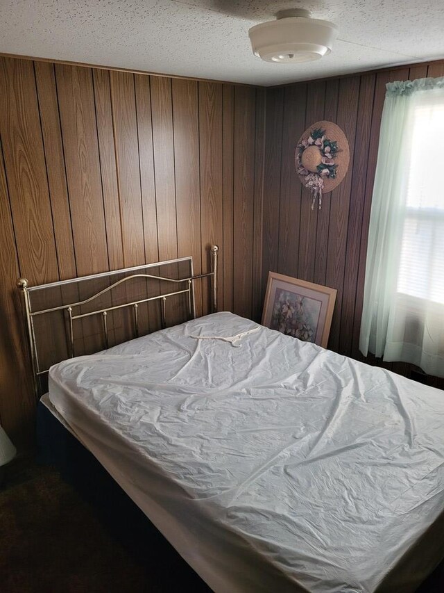 bedroom with wooden walls and a textured ceiling
