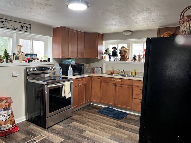 kitchen featuring a healthy amount of sunlight, dark wood-type flooring, black appliances, and sink