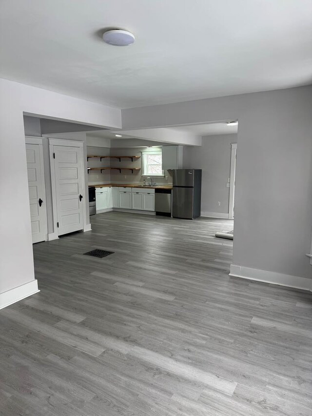 unfurnished living room with sink and light hardwood / wood-style flooring