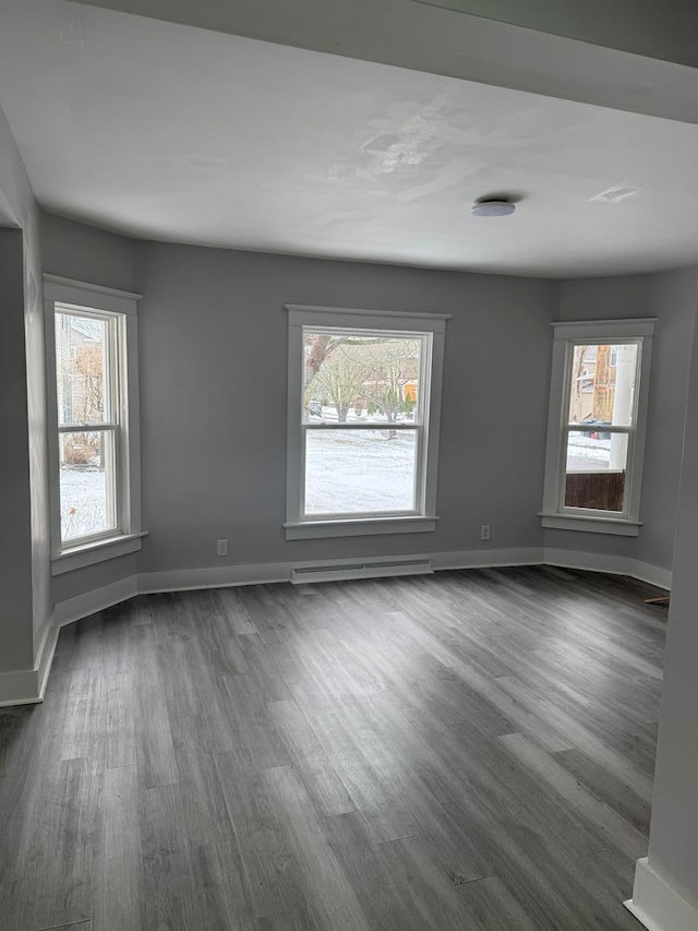 empty room with a baseboard heating unit and dark wood-type flooring