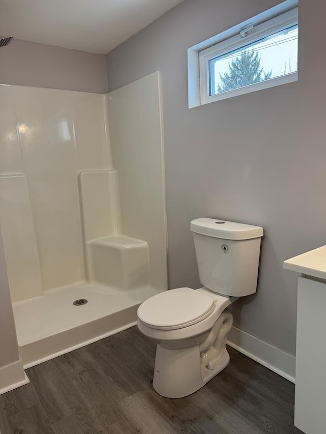 bathroom featuring hardwood / wood-style flooring, a shower, and toilet