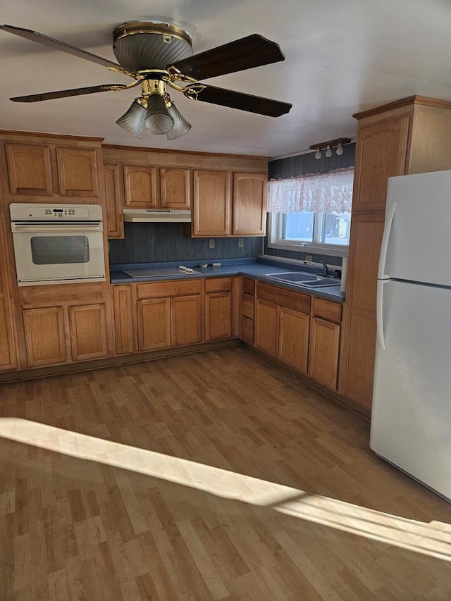 kitchen with sink, white appliances, wood-type flooring, and ceiling fan