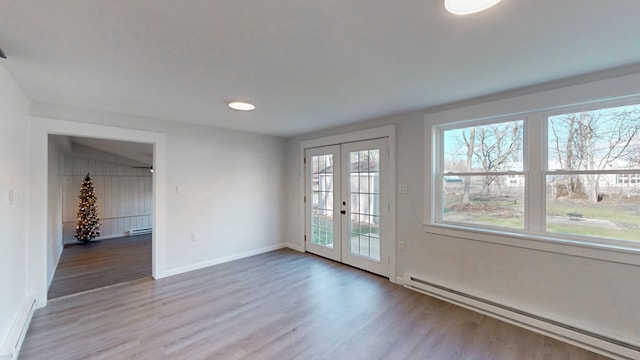 interior space with light hardwood / wood-style flooring, baseboard heating, and french doors