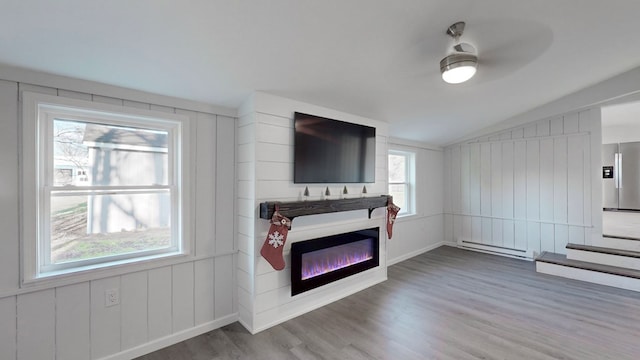 living room with wood-type flooring, lofted ceiling, plenty of natural light, and a baseboard heating unit