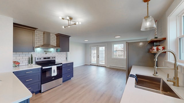 kitchen with sink, wall chimney exhaust hood, hanging light fixtures, light hardwood / wood-style floors, and stainless steel range with electric cooktop