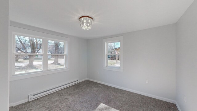 spare room featuring baseboard heating, a wealth of natural light, and carpet