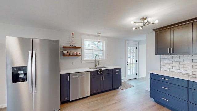 kitchen with decorative backsplash, light wood-type flooring, stainless steel appliances, sink, and a chandelier