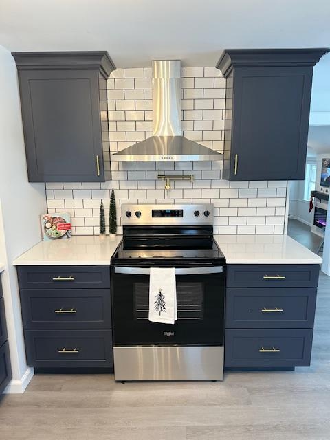 kitchen featuring wall chimney range hood, decorative backsplash, light hardwood / wood-style flooring, and stainless steel range with electric stovetop