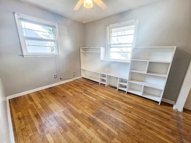 interior space featuring hardwood / wood-style flooring, ceiling fan, and multiple windows