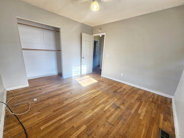 unfurnished bedroom featuring hardwood / wood-style floors, a closet, and ceiling fan