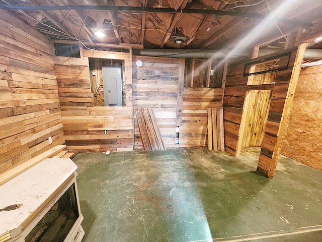 basement featuring electric panel and wooden walls