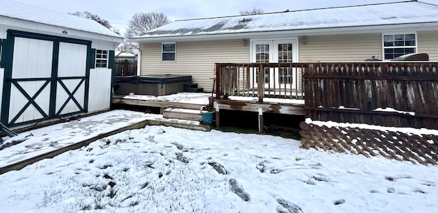 snow covered deck with a shed and a hot tub