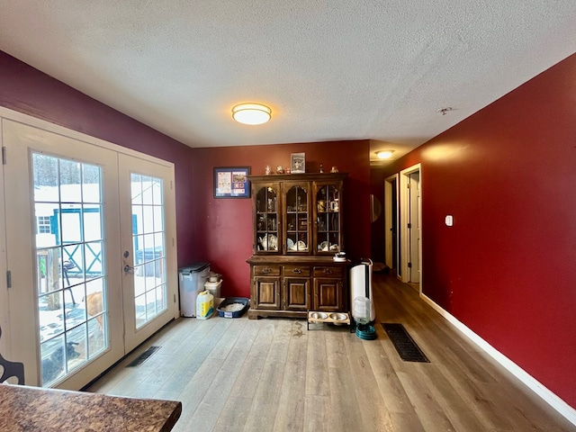 interior space with french doors, a textured ceiling, and light hardwood / wood-style floors