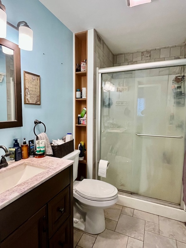 bathroom with tile patterned flooring, a shower with door, vanity, and toilet