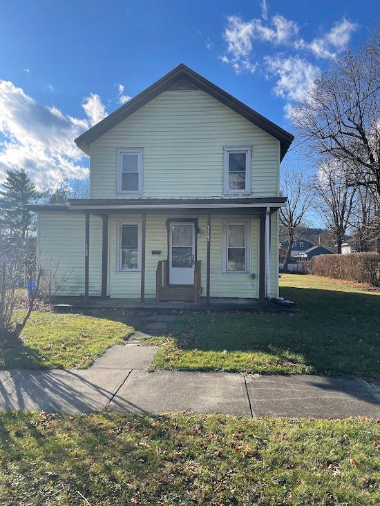 view of front of property featuring covered porch and a front lawn