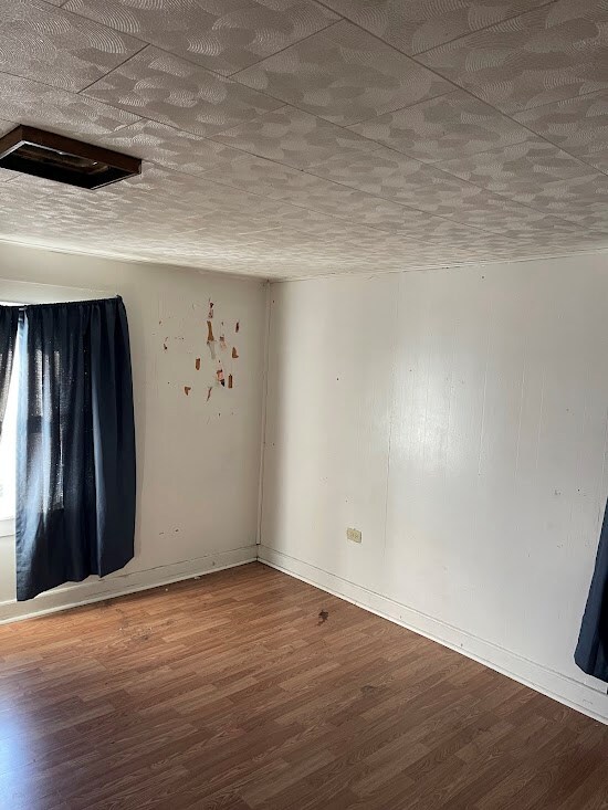 unfurnished room with wood-type flooring and a textured ceiling