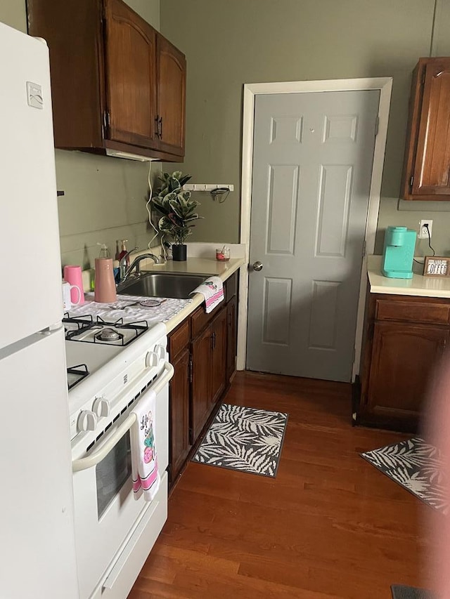 kitchen with sink, dark wood-type flooring, and white appliances