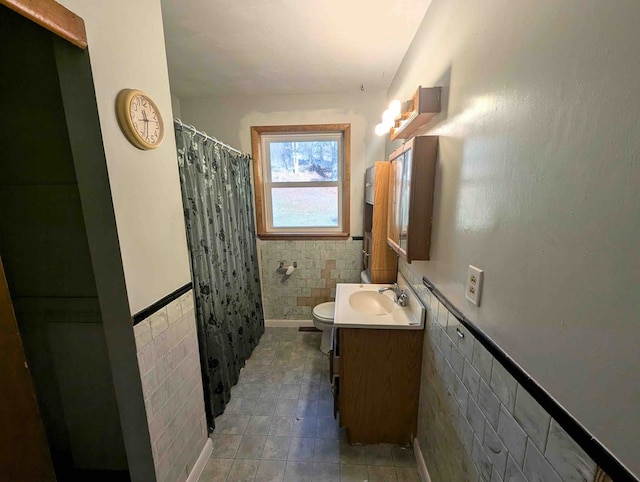 bathroom featuring vanity, toilet, tile walls, and walk in shower