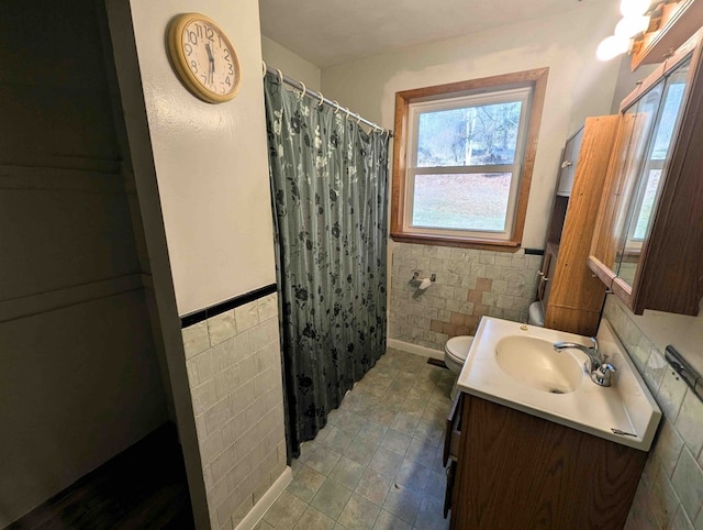 bathroom with walk in shower, vanity, tile walls, and toilet