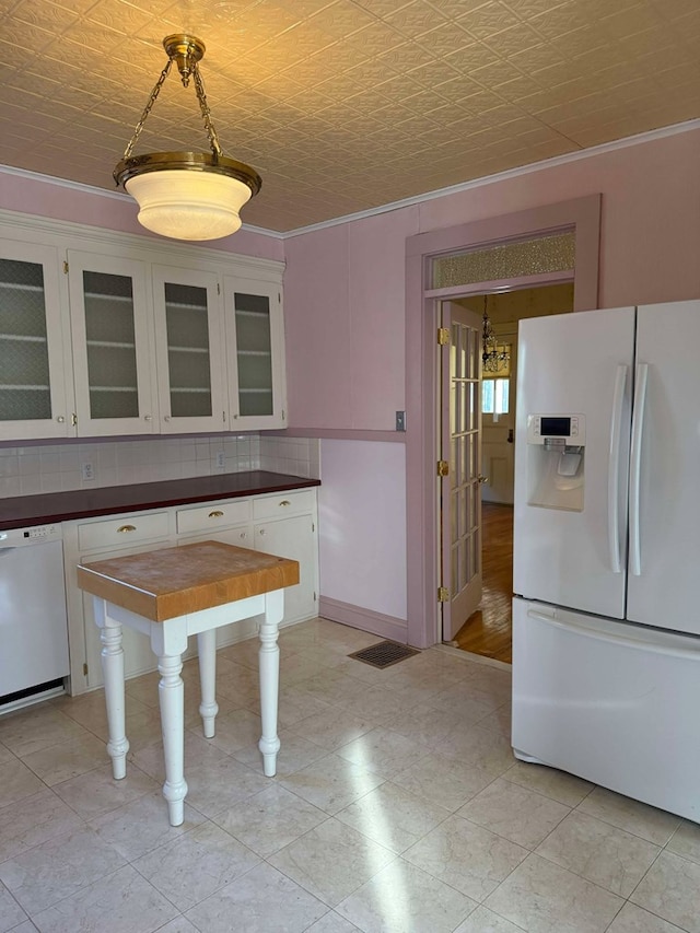 kitchen with white appliances, decorative backsplash, ornamental molding, a notable chandelier, and white cabinetry