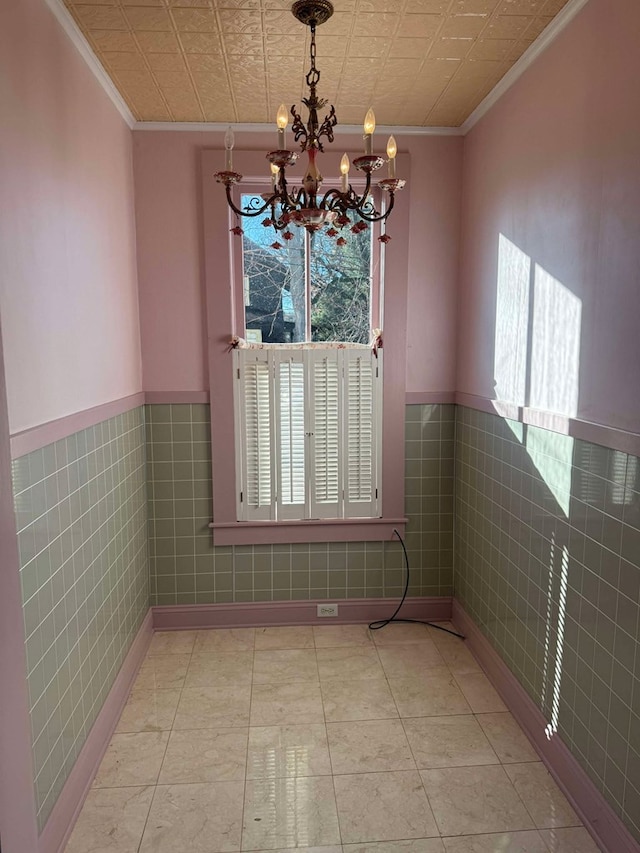 unfurnished dining area with a chandelier, plenty of natural light, tile walls, and ornamental molding