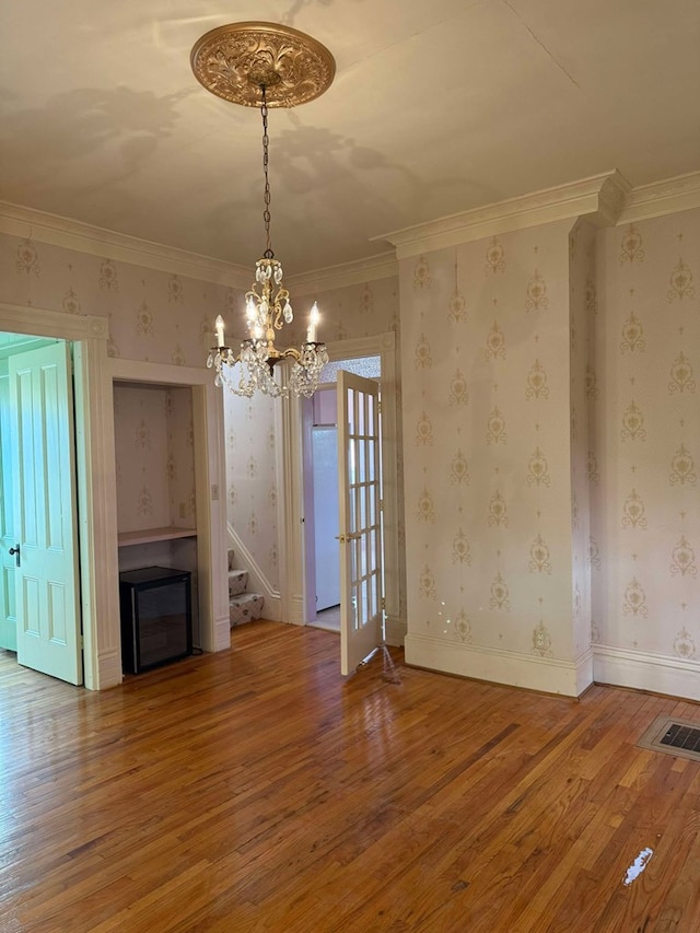 unfurnished living room with hardwood / wood-style flooring, ornamental molding, and a chandelier