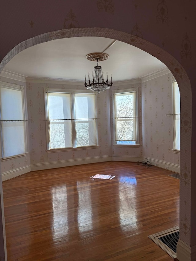 unfurnished dining area with light wood-type flooring, crown molding, and an inviting chandelier