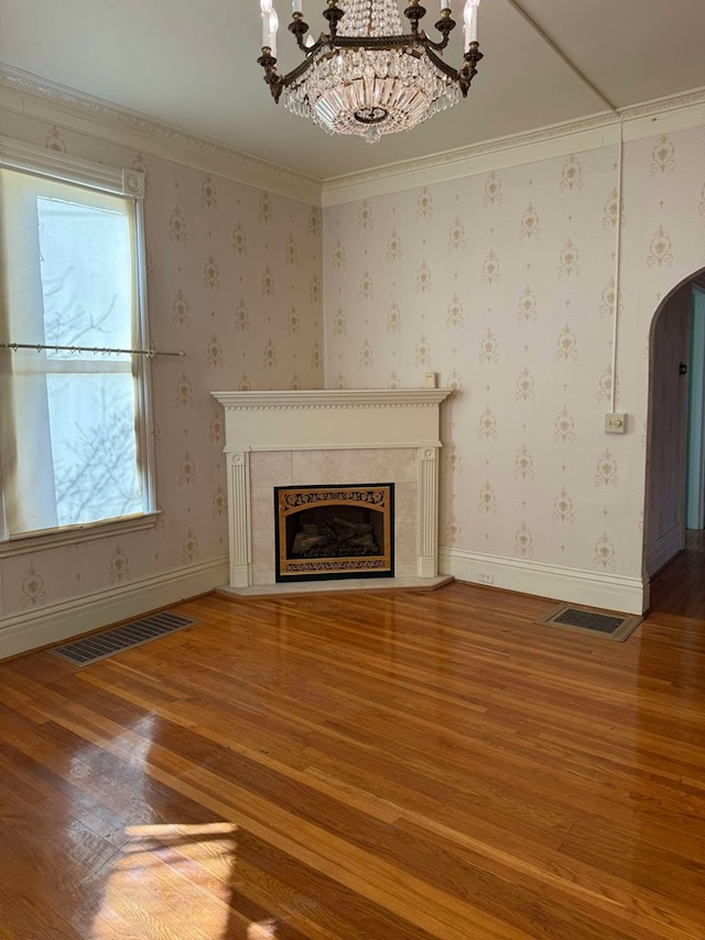 unfurnished living room featuring crown molding, a chandelier, and hardwood / wood-style flooring