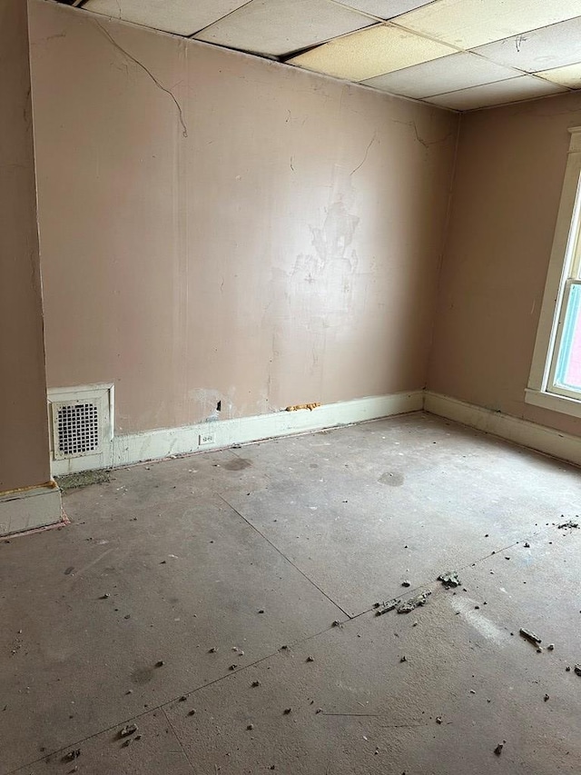 unfurnished room featuring baseboards, visible vents, and a drop ceiling