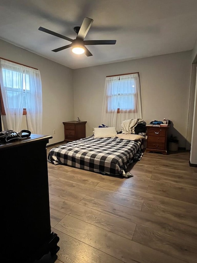 bedroom with multiple windows, wood-type flooring, and ceiling fan