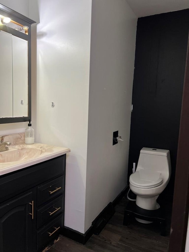 bathroom with hardwood / wood-style flooring, vanity, and toilet